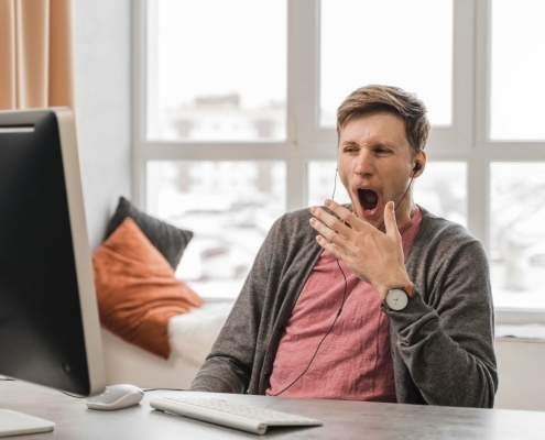 ragazzo al computer che sta lavorando e sbadiglia