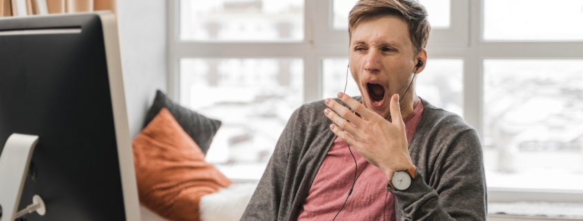 ragazzo al computer che sta lavorando e sbadiglia