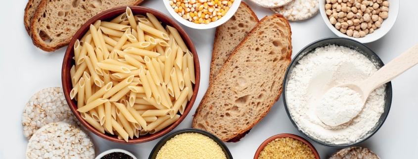 vista dall'alto di vari alimenti contenenti glutine tre cui pane e pasta