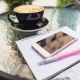 tavolo con penna, quaderno, cellulare e cappuccino sullo sfondo